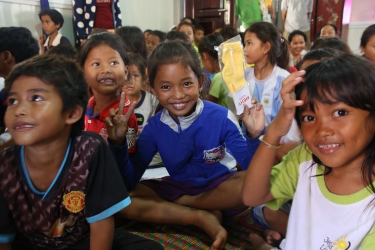캄보디아 아이들이 미하이삭스 양말을 들고 웃는 표정으로 카메라를 응시하고 있습니다.